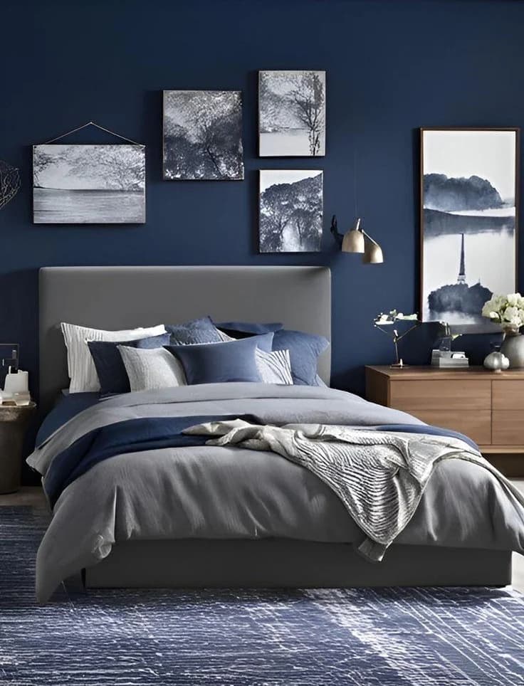 Blue and gray bedroom with landscape art and natural wood furniture.