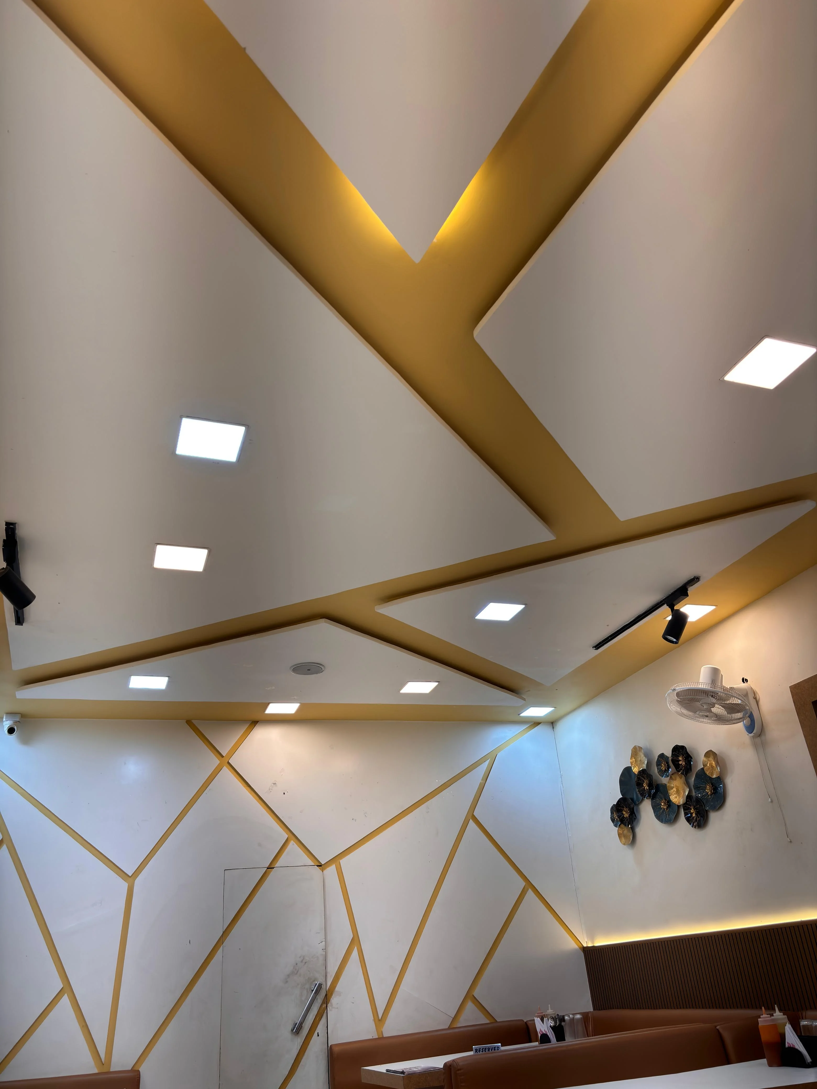 Modern restaurant interior with geometric ceiling, recessed lighting, and decorative wall accents.