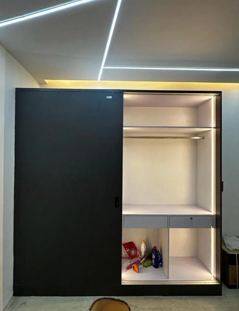 Modern wardrobe with sliding black door and LED lighting. Interior shows shelves and storage.